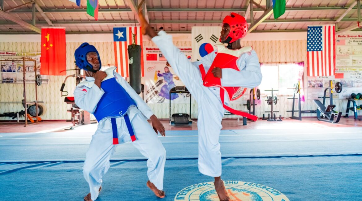 Liberia Taekwondo National Tournament announcement photo with two competitors fighting in gym.