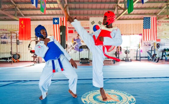 Liberia Taekwondo National Tournament announcement photo with two competitors fighting in gym.